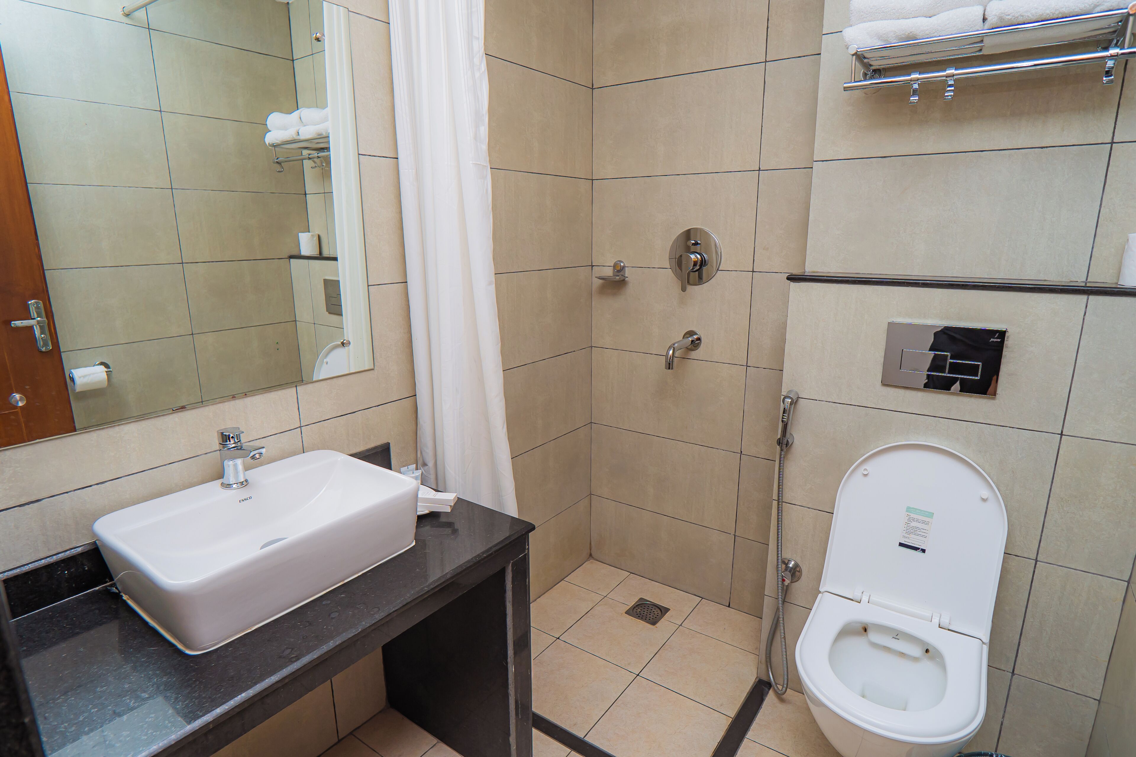 Un baño con lavamanos, inodoro, ducha y espejo.