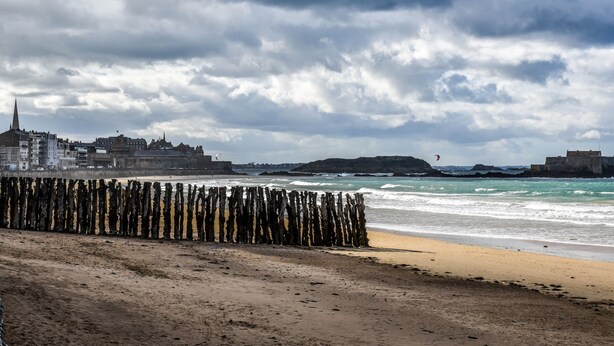 A beach with a wooden fence, a sandy shore, and buildings in the background. - Ker Lucienne" 50m from the "sillon" beach in the center of town, 12 minutes from the city center and the TGV train station. (Saint-Malo)