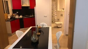 Une cuisine moderne avec des meubles rouges, un plan de travail noir et une table à manger avec des chaises blanches.