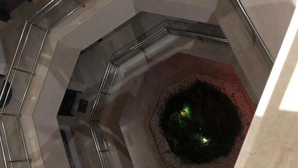 Un escalier en colimaçon doté de rampes en verre et d’un espace circulaire central avec une surface réfléchissante.