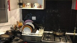 Une cuisine de taille réduite avec un plan de travail noir, des placards rouges et une cuisinière.