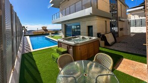 Une maison moderne à deux étages dotée d’une piscine, d’un espace salon extérieur et d’un jacuzzi.