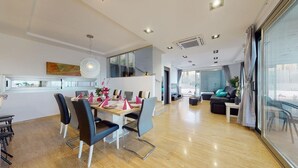 Un salon moderne avec un coin repas, de grandes fenêtres et une vue sur la ville.