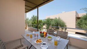 Un balcón con una mesa dispuesta para el desayuno, que incluye croissants, fruta y bebidas.