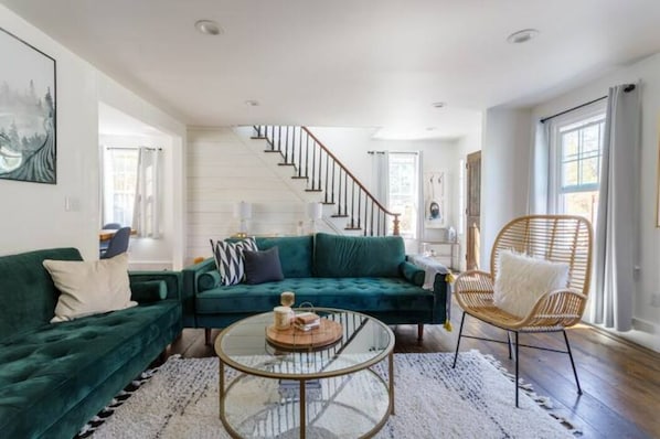 A modern living room with a green sofa, a wicker chair, and a glass coffee table.