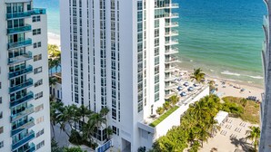Un hotel de gran altura con varios balcones que dan a una playa y al océano.