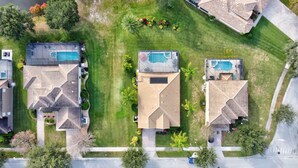 A residential area with three houses, each featuring a swimming pool and a well-maintained lawn. - Heatable pool and Spa, propane grill, 3 King beds, 4 Twins, TV each bedroom (Kissimmee)