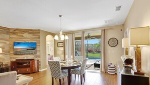 A dining area with a round table, chairs, and a television on the wall. - Heatable pool and Spa, propane grill, 3 King beds, 4 Twins, TV each bedroom (Kissimmee)