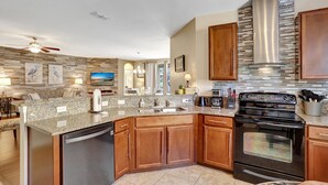 A modern kitchen with granite countertops, wooden cabinets, a stainless steel range hood, and a dishwasher. - Heatable pool and Spa, propane grill, 3 King beds, 4 Twins, TV each bedroom (Kissimmee)