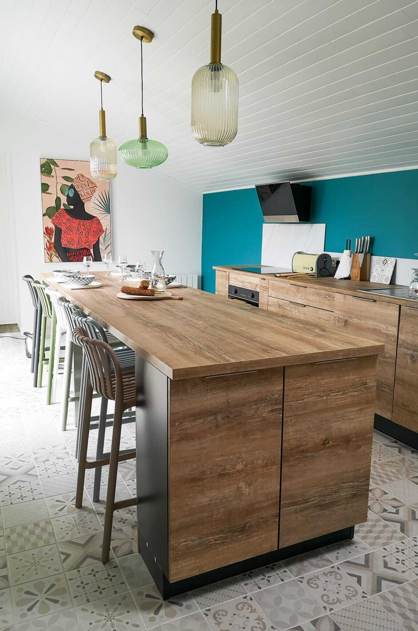 Een moderne keuken met een houten kookeiland, barkrukken en hanglampen.