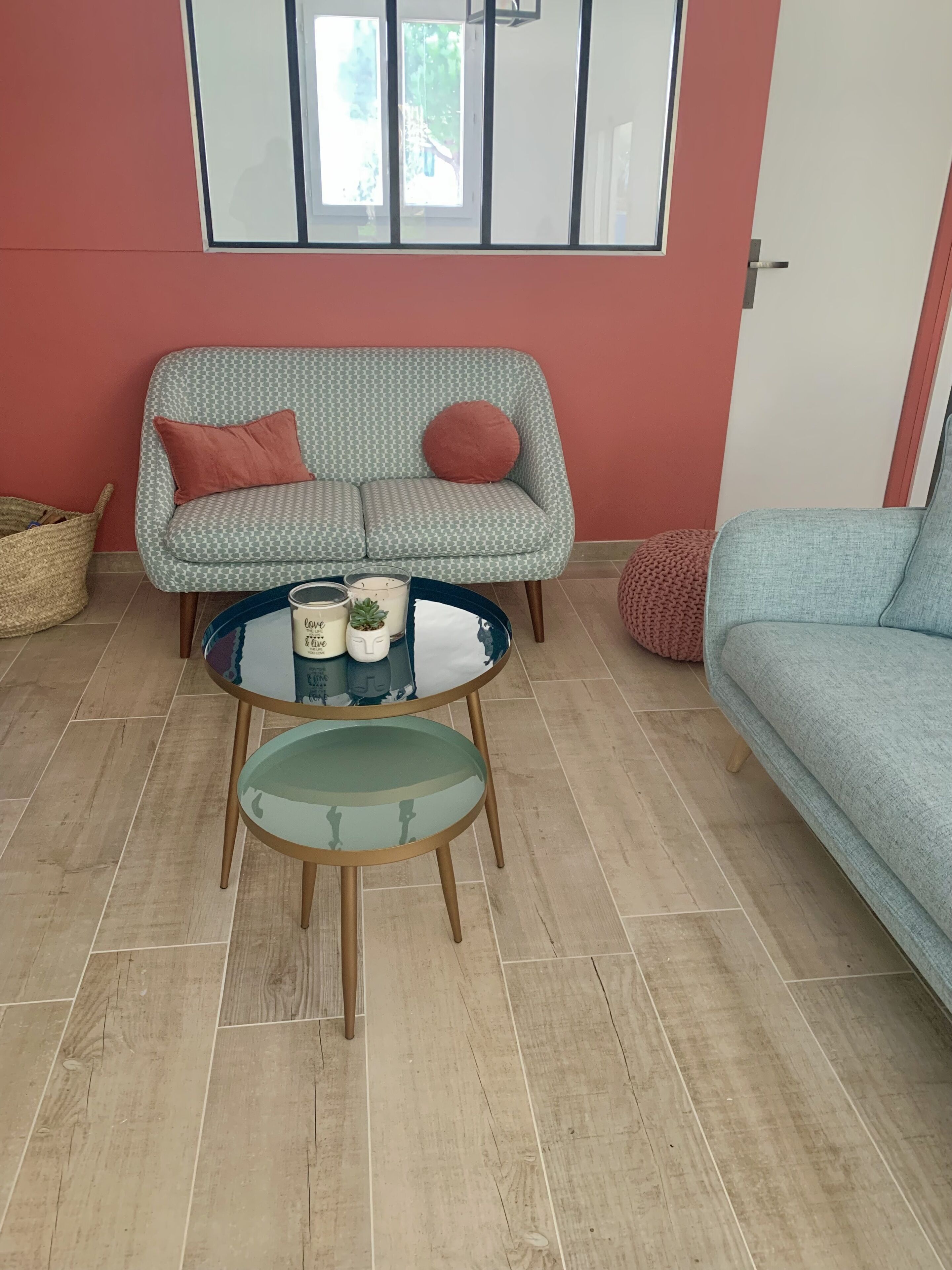 A living room with a patterned sofa, a round glass table, and a blue sofa.