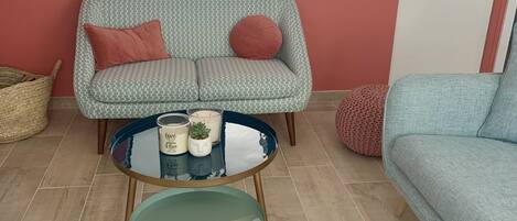 A living room with a patterned sofa, a round glass table, and a blue sofa.