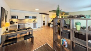 A modern kitchen with white cabinets, a microwave, and a dining area with a bench. - Direct location on the edge of the forest with high-quality wellness area Pet-friendly! (Furth im Wald)