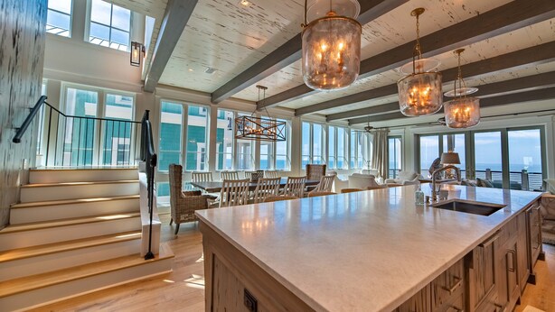 A spacious kitchen with a large island, wooden beams, and large windows offering views of the ocean. - Luxury beach-front home, gourmet kitchen, private pool, gated community, gear (Port Saint Joe)