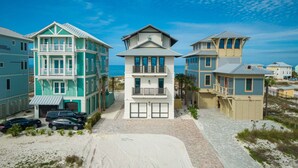 A beachfront property with multiple-story buildings, a paved driveway, and parked cars. - Luxury beach-front home, gourmet kitchen, private pool, gated community, gear (Port Saint Joe)
