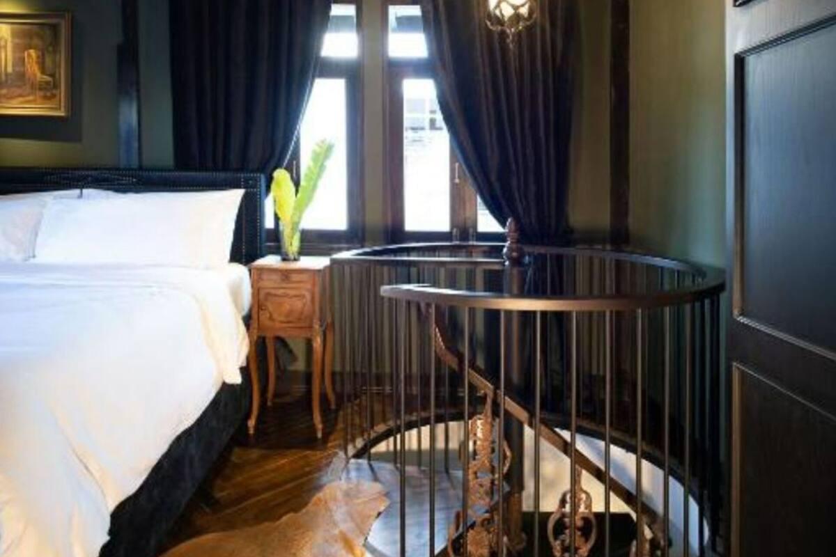 A bedroom with a bed, a nightstand, a circular staircase, and a chandelier.