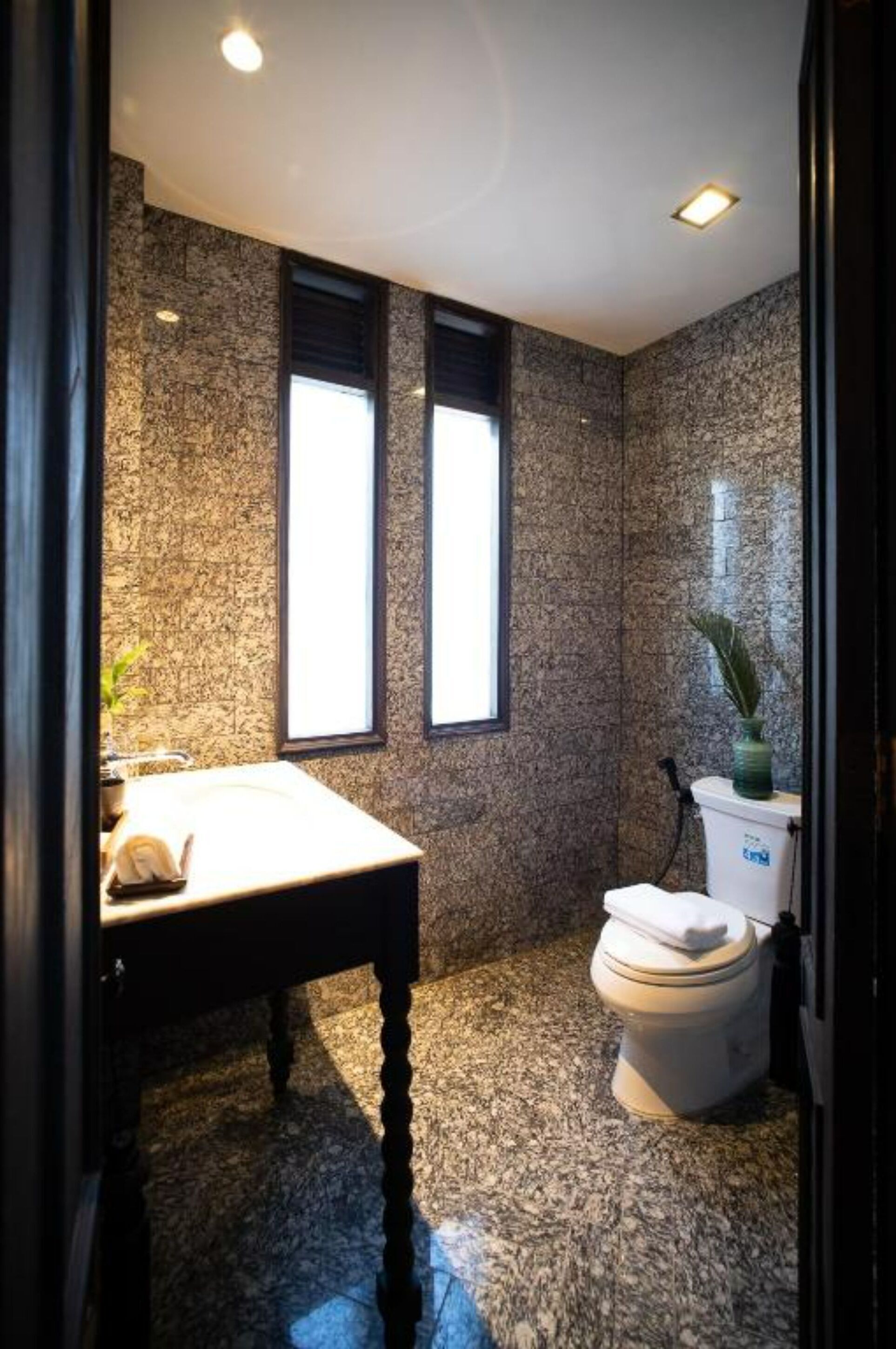 Un baño con paredes de granito, un lavamanos blanco y un inodoro.