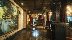A spacious lobby with a large mural, wooden flooring, and classic furniture. - Baan Tuk Din Hotel (Bangkok)