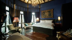 A room with a large bed, a chandelier, a sofa, and a dining table with glasses. - Baan Tuk Din Hotel (Bangkok)