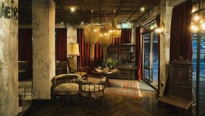 A vintage interior with wooden floors, a chandelier, and red curtains. - Baan Tuk Din Hotel (Bangkok)