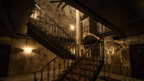 A dimly lit staircase with ornate metal railings and a skeleton display. - Baan Tuk Din Hotel (Bangkok)