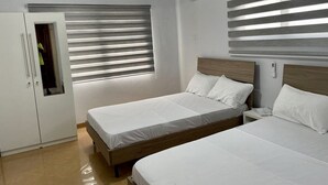 Un dormitorio con dos camas, un armario y una ventana con persianas.