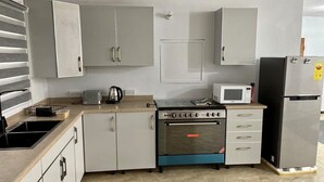 Una cocina con armarios blancos, estufa, microondas y refrigerador.