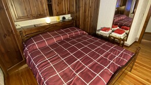 Une chambre à coucher avec un cadre de lit en bois, un grand miroir et un plancher en bois.
