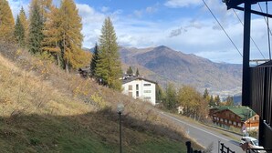 Un sentier qui mène à un bâtiment d’où l’on peut admirer des montagnes et une ville au loin.