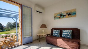A room with a brown sofa, a table with a lamp, and a painting on the wall. - L' Amandier with communal swimming pool (AJACCIO)