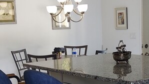 A kitchen with a bar area, featuring a chandelier, bar stools, and a granite countertop.