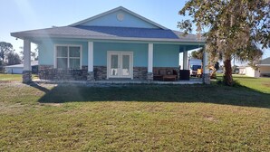 A house with a covered porch, a stone foundation, and a blue roof.