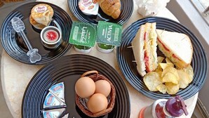 Uma mesa com diversos alimentos, incluindo sanduíches, batatas fritas, ovos e acompanhamentos.