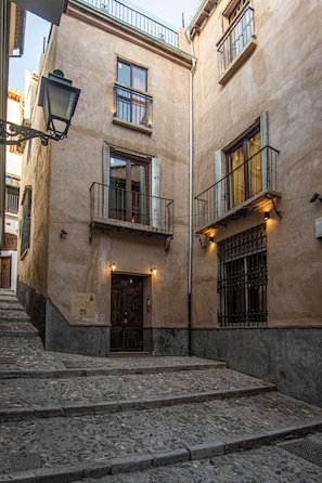 Un edificio con fachada de piedra, puerta de madera y una escalera que lleva a la entrada.