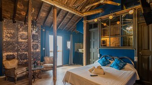 A room with a bed, a chair, a table, and a window. - Apartamentos CV (Granada)