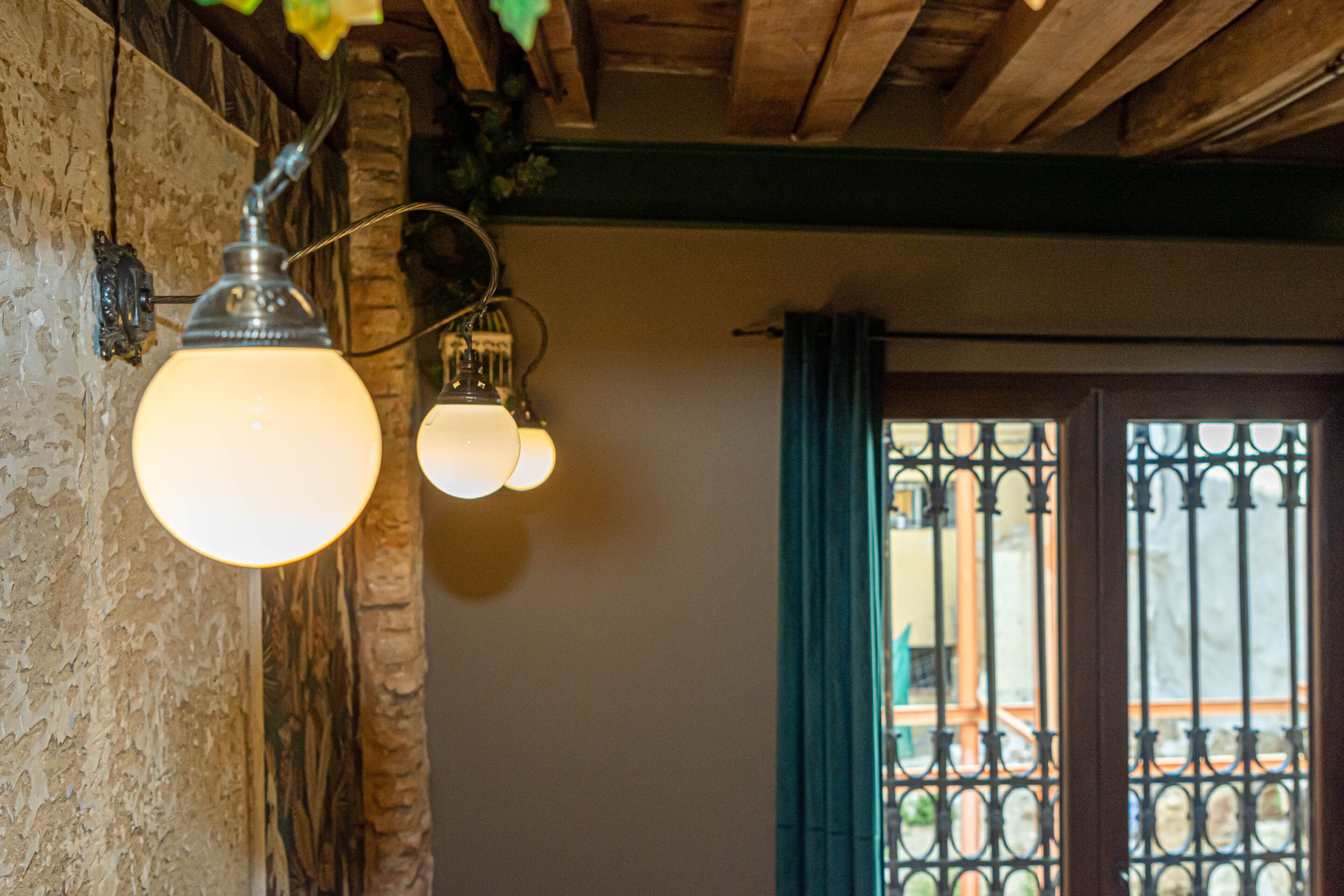 Una habitación con techo de madera rústica, pared con textura y ventana con rejas.
