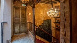 A wooden staircase with a chandelier, a door with a light switch, and a patterned floor. - Apartamentos CV (Granada)