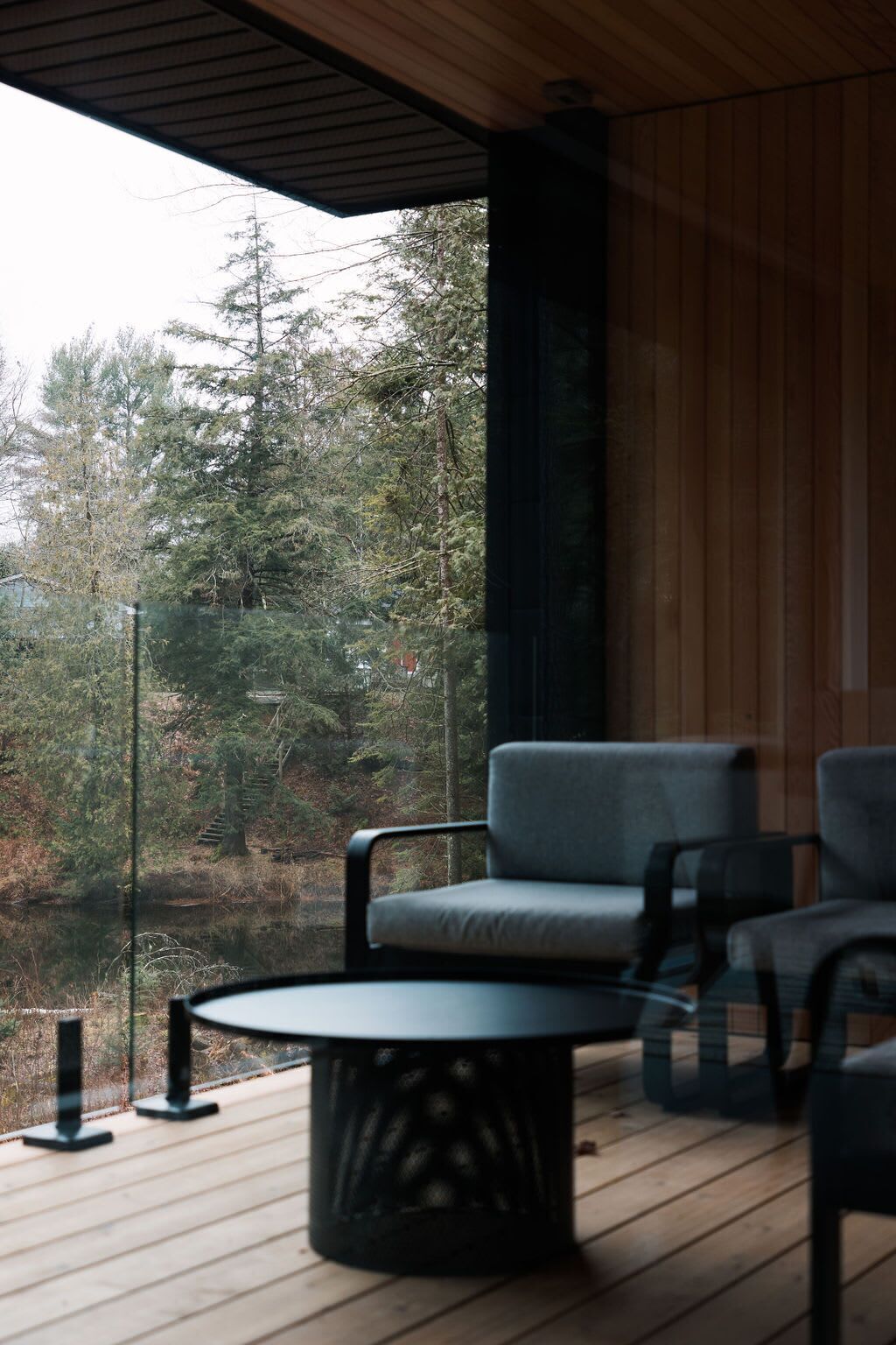 Une terrasse en bois avec une table ronde et deux chaises, donnant sur une zone boisée.