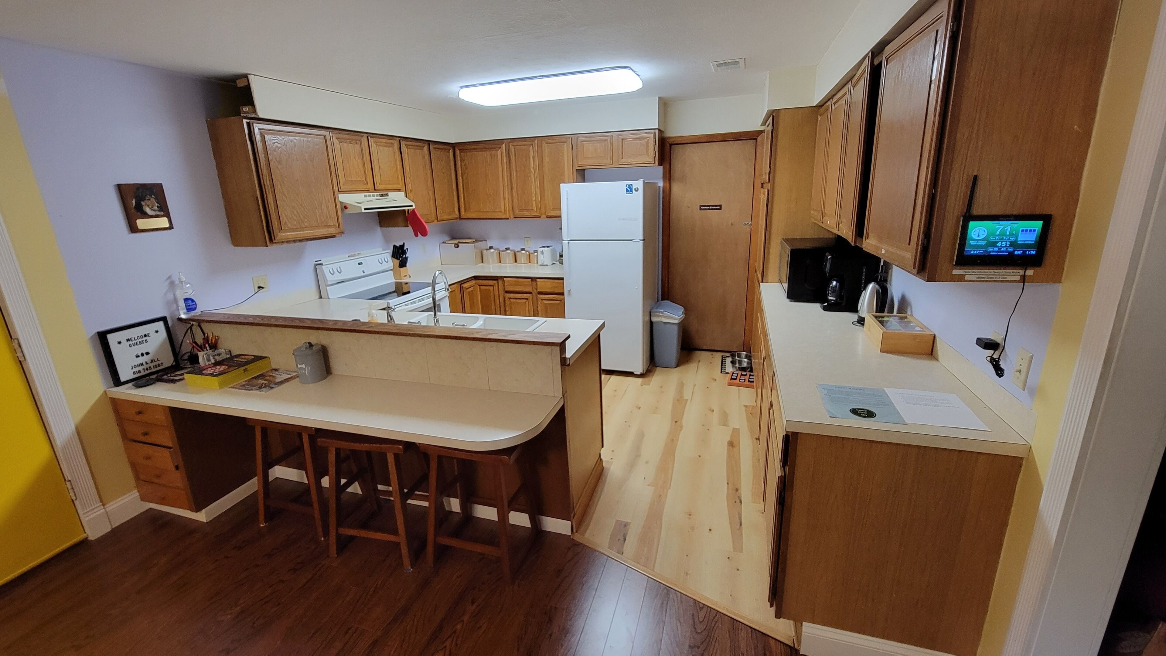A compact kitchen with wooden cabinets, a white refrigerator, a stove, and a small bar area.