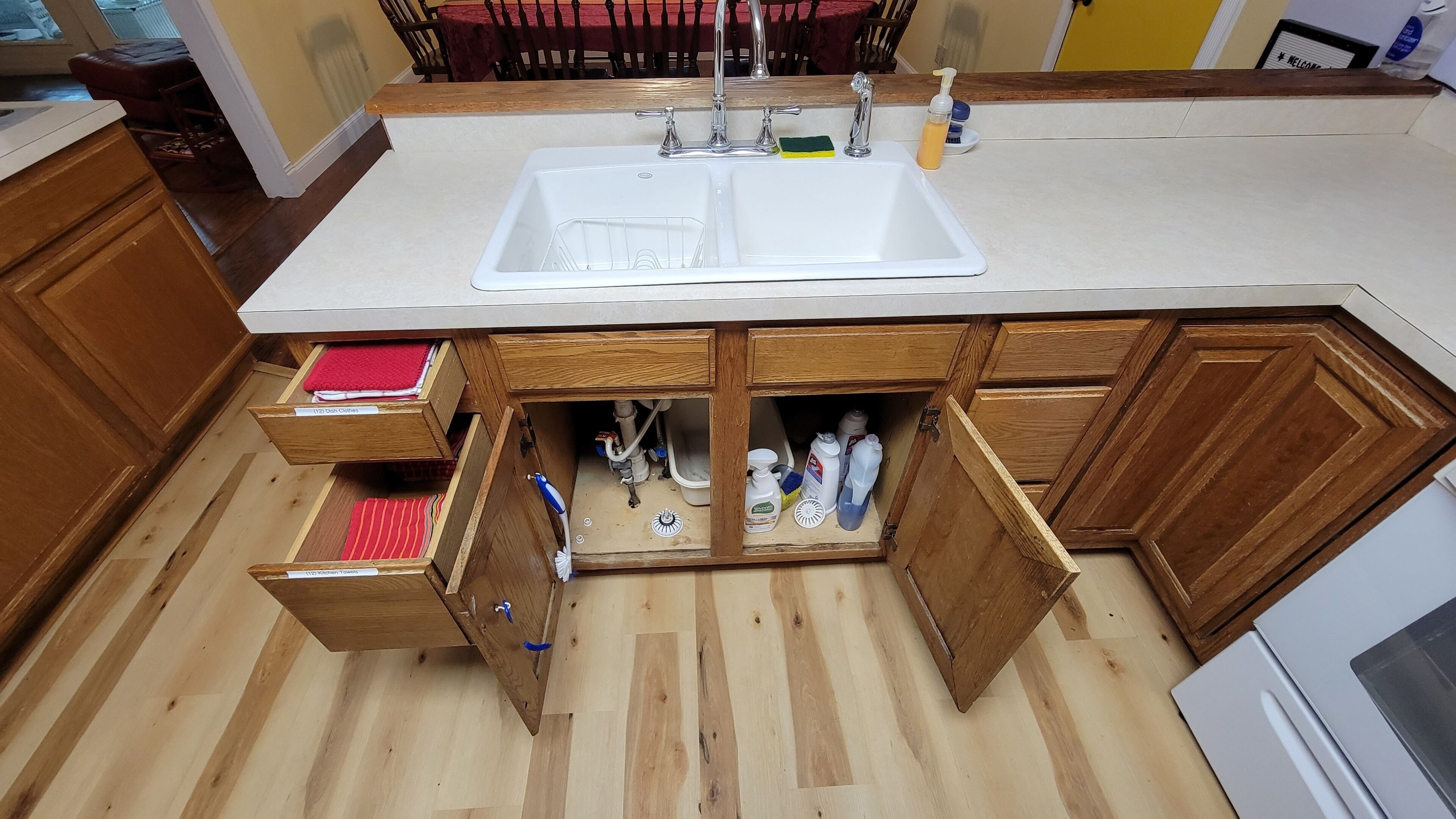 Een keuken met een witte spoelbak, houten kastjes en een ingebouwde vaatwasser.