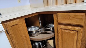 A kitchen with wooden cabinets, a white countertop, and stainless steel cookware. - Relax at this Private, Peaceful, Dog-Friendly Ecohouse in the Woods. (Lowell)