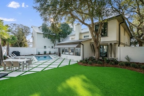 Una casa moderna con piscina, mobiliario exterior y césped cuidado.