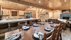 A spacious kitchen with wooden cabinets, a central island, and a dining area set for six. - Best Location 5BR Sleeps 16 (Pigeon Forge)