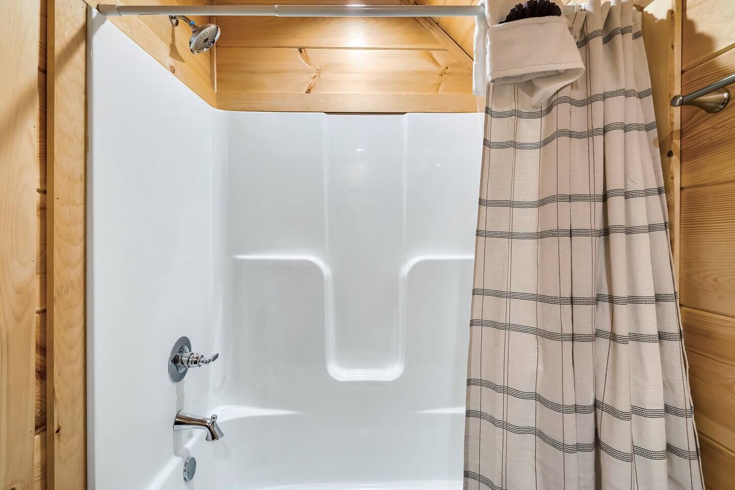 A bathroom with a bathtub, a shower, and a wooden ceiling.