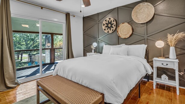 A bedroom with a large bed, a ceiling fan, a nightstand with a lamp, and a view of the outdoors. - Modern Lake House 2 Units, Pool, Lake 3Min, Pets (Somerville)