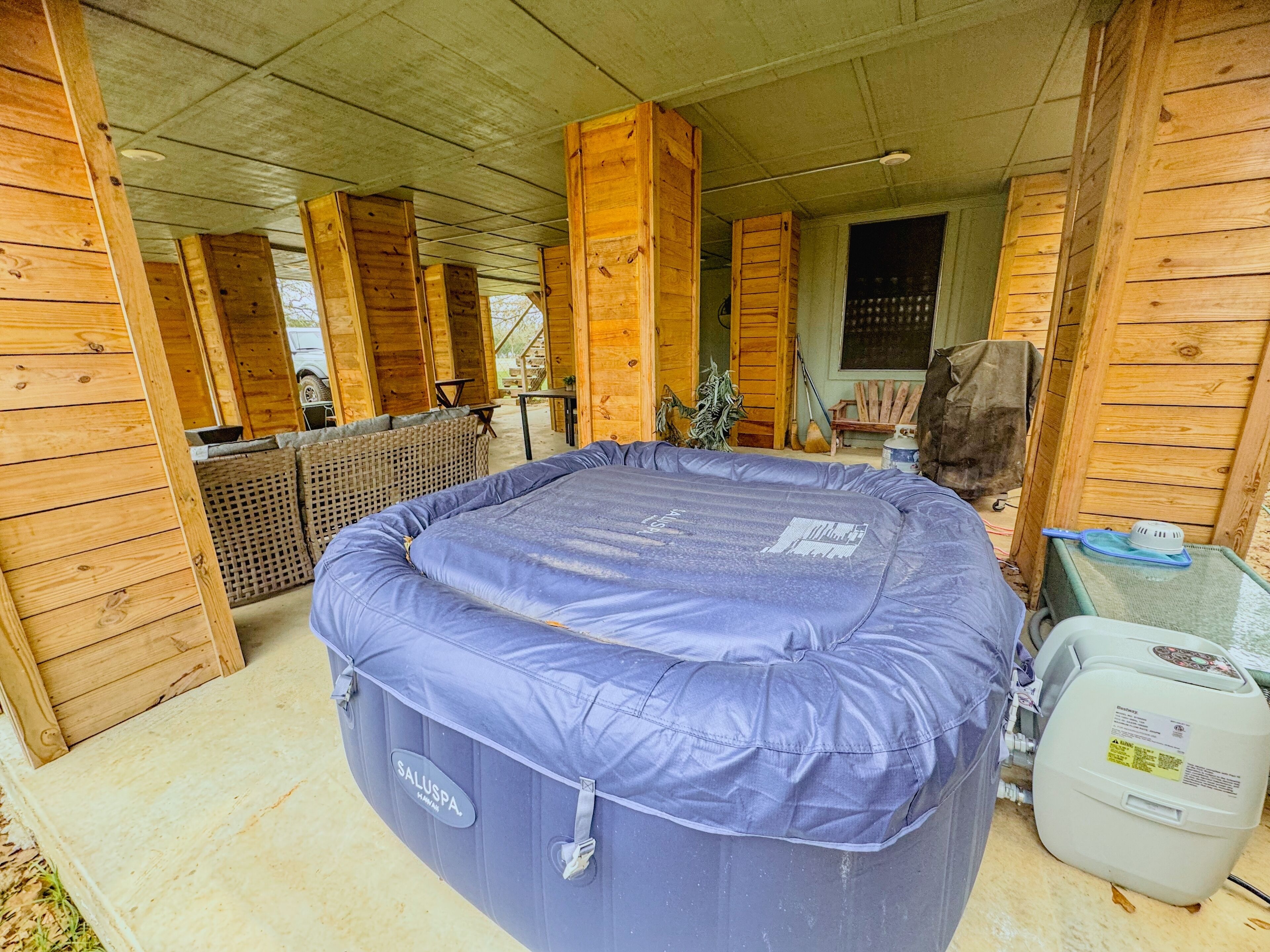 Una habitación con una cama hinchable grande, paredes de madera y una ventana.