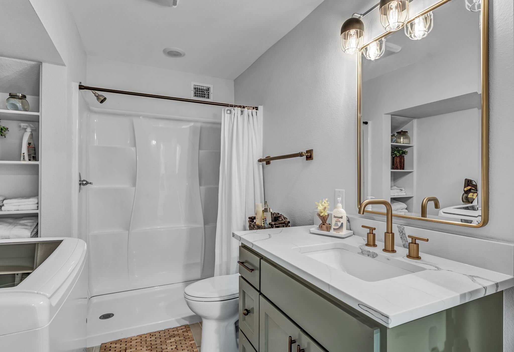Une salle de bain moderne avec une baignoire blanche, des toilettes, un meuble-lavabo avec un grand miroir et un rideau de douche.