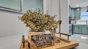 A kitchen area with a microwave popcorn container, a decorative plant, and a vintage-style popcorn popper on a wooden tray. - Modern Lake House 2 Units, Pool, Lake 3Min, Pets (Somerville)
