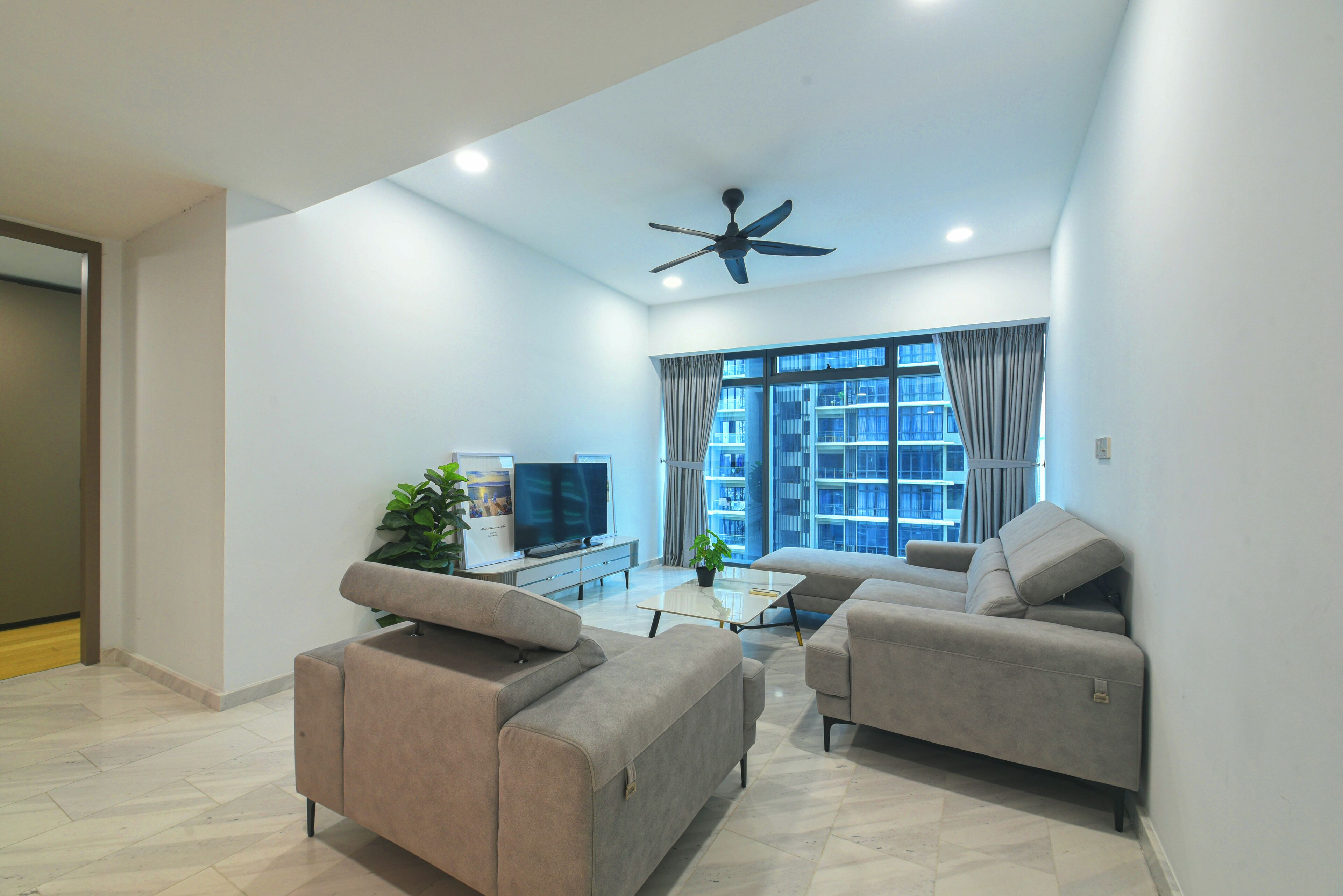 A modern living room with two sofas, a coffee table, a TV, and a ceiling fan.