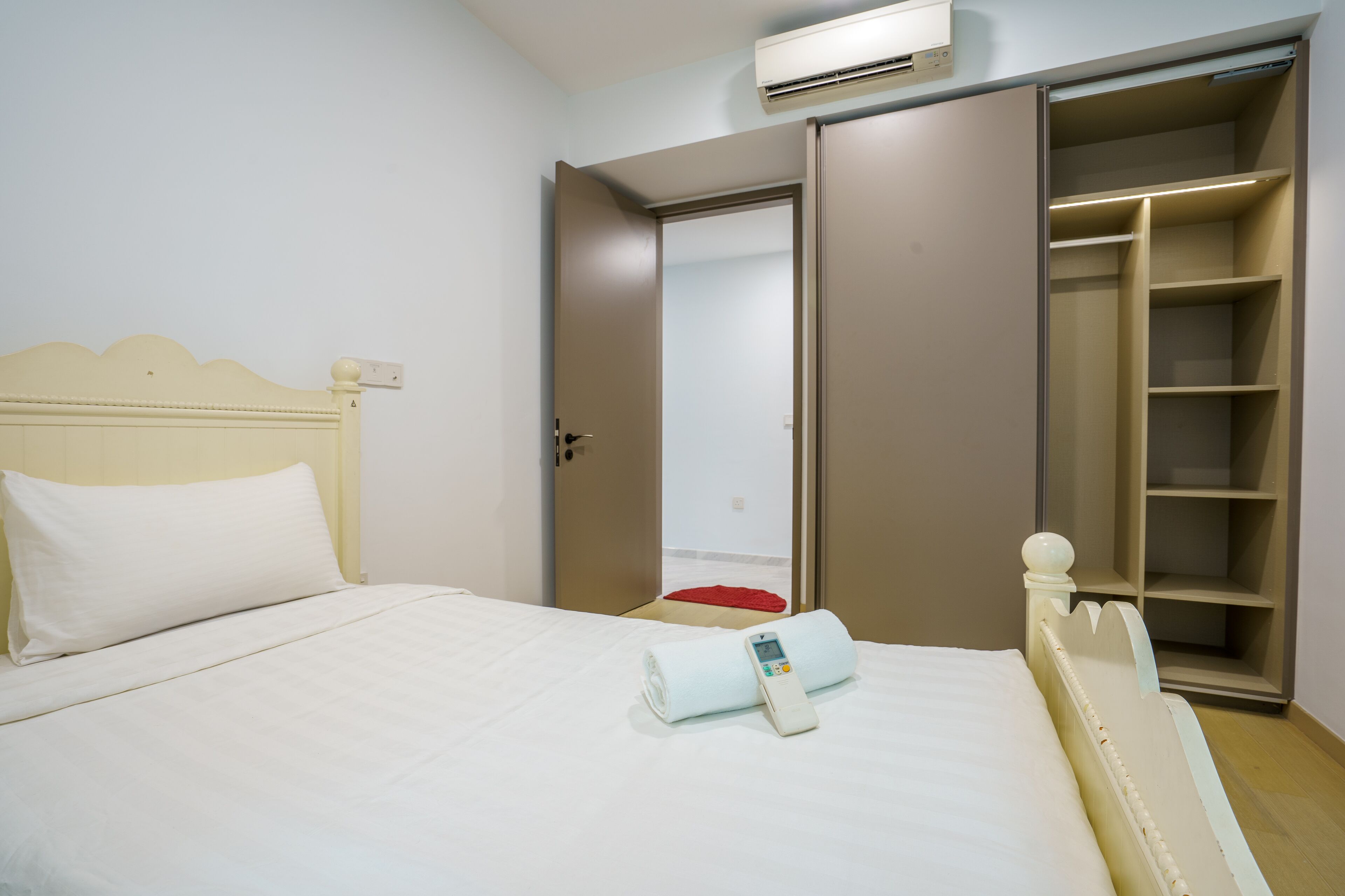 A hotel room with a bed, a wardrobe, and an air conditioning unit.
